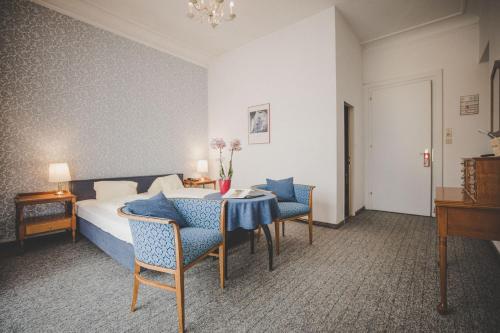 a hotel room with a bed and a table and chairs at Kurhotel & Hotel Mozart in Bad Gastein
