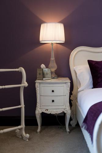 a bedroom with a bed and a nightstand with a lamp at The Swan Hotel in Clitheroe