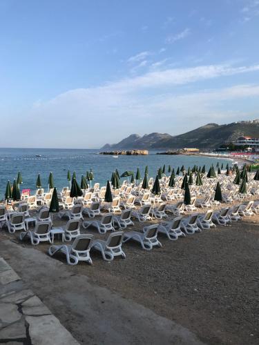 a group of chairs and umbrellas on a beach at Apartmani Belma in Dobra Voda