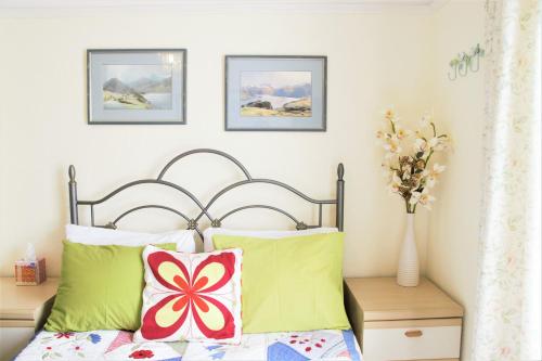 チチェスターにあるThe Witterings Bed and Breakfastのベッドルーム1室(緑と赤の枕が備わるベッド1台付)