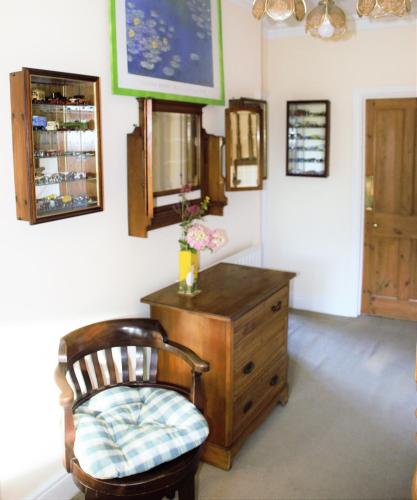 Cette chambre comprend une chaise et une commode en bois. dans l'établissement The Witterings Bed and Breakfast, à Chichester