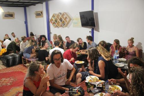 Eine Gruppe von Menschen, die an Tischen sitzen und Essen essen. in der Unterkunft Sunset Surfhouse Morocco in Tamraght Ouzdar