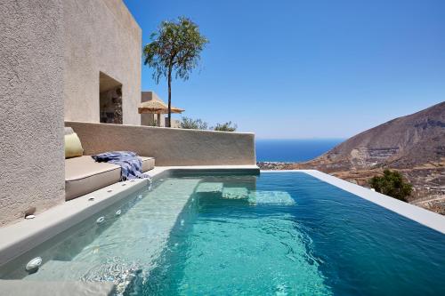 a swimming pool in front of a house with a view of the ocean at Aeon Suites - Adults Only in Pirgos
