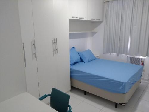 Un pequeño dormitorio con una cama azul y una silla en Seu Cantinho, en Río de Janeiro