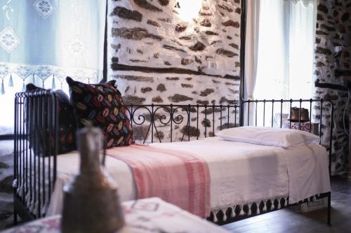 a bedroom with a bed and a stone wall at Filoxenia- Drakia in Drakeia
