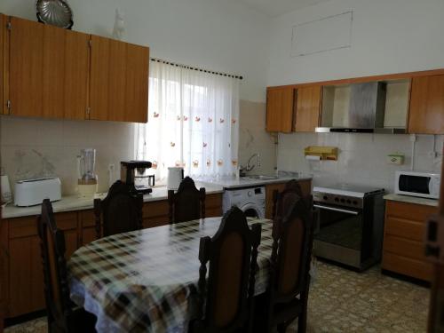 eine Küche mit einem Tisch mit Stühlen, einem Tisch und einem Tisch sowie einer Küche in der Unterkunft Casa Conceição in Atalaia