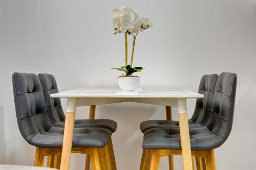 a table with two chairs and a vase with a flower on it at Villa Floris in Mostar