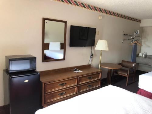 a hotel room with a bedroom with a bed and a television at Rexdale Inn in Seminole