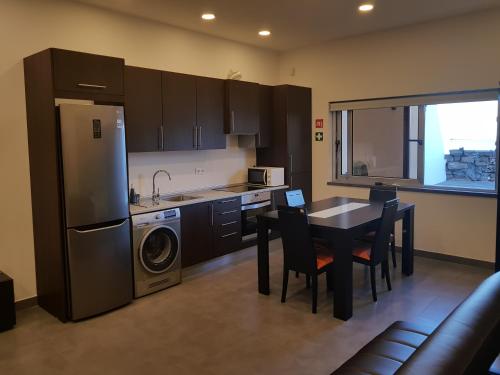 a kitchen with a table and a sink and a refrigerator at Black House in Praia da Vitória