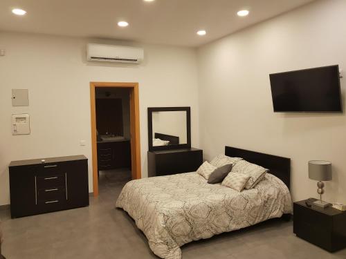 a bedroom with a bed and a tv on the wall at Black House in Praia da Vitória