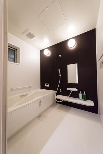 a bathroom with a tub and a sink and a mirror at KIZUNA HOTEL Gojo Kiyomizu-dera Kamogawa in Kyoto