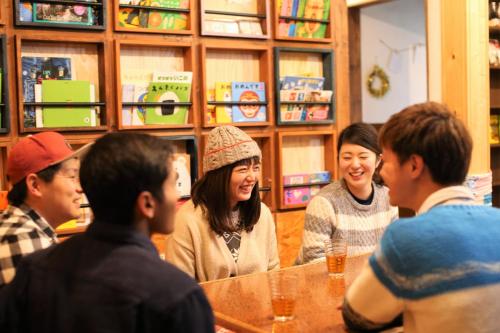 eine Gruppe von Menschen, die in einem Restaurant um einen Tisch herum sitzen in der Unterkunft Guesthouse Kakehashi in Kesennuma