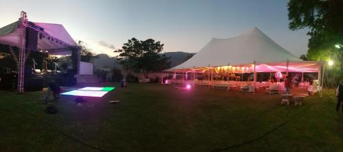 a tent with tables and chairs in a field at night at Hotel Pasabien in Huité