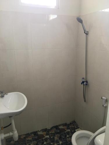 a white bathroom with a sink and a shower at LG Homestay in Kepanjen
