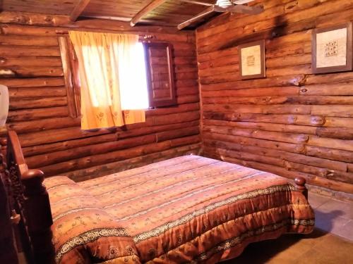 1 dormitorio con 1 cama en una cabaña de madera en Posada la Cabaña en 