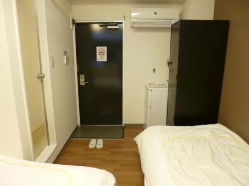 a room with a black door and two beds at OUCHI HOTEL Yokogawa in Hiroshima