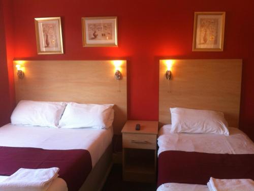 two beds in a hotel room with red walls at City Inn Express Hotel in London