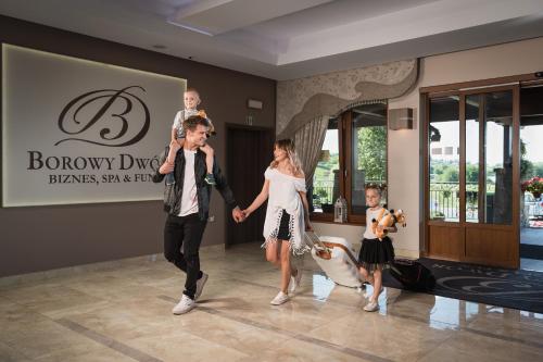 a man and a woman and two children walking through a lobby at Borowy Dwór- Biznes, Spa & Fun in Szaflary