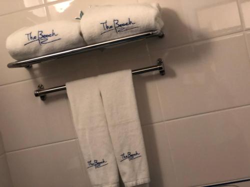 a bathroom with towels with the beach written on them at Seaside Hotel The Beach in Chatan