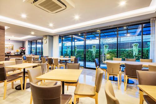 a restaurant with tables and chairs and large windows at Livotel Hotel Kaset Nawamin Bangkok in Bangkok