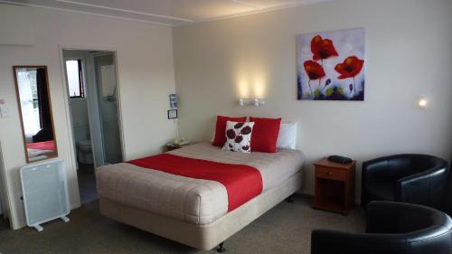 a bedroom with a bed and a chair in it at ASURE Adcroft Motel in Ashburton