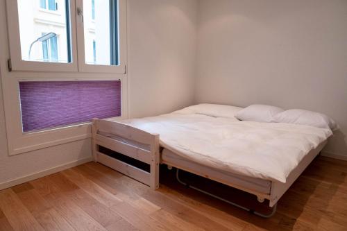 um pequeno quarto com uma cama e uma janela em Family apartment near the train station em Vevey