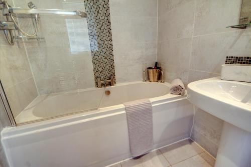 a white bathroom with a tub and a sink at Chapelhill in Helensburgh
