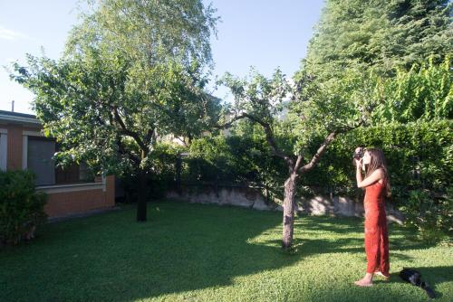 a woman in a red dress standing next to a tree at Casetta del Molo in Mandello del Lario