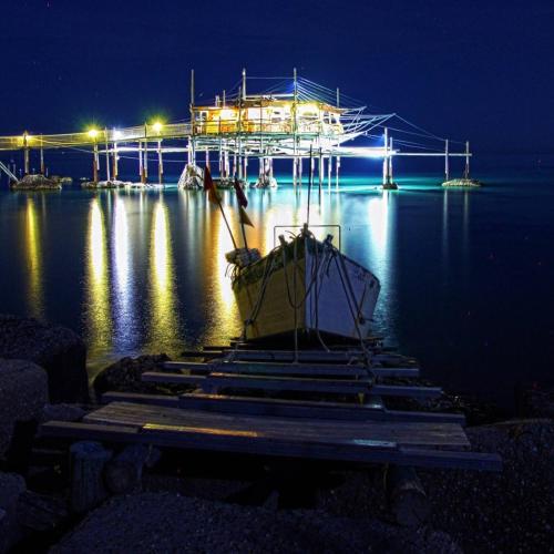 a boat sitting on the water at night at Al Faro Bianco B&B e Residence con parcheggio in Vasto