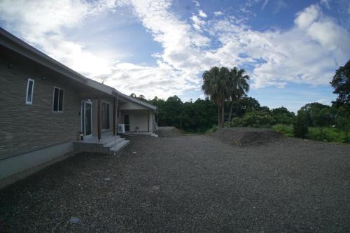a house with a gravel yard next to a palm tree at Yakunoyado Taguchi in Yakushima