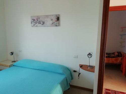 a bedroom with a blue bed and a table at Apartment The Sea of Sardinia in Putzu Idu