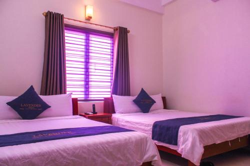 two beds in a room with a window at Lavender Hotel in Dong Hoi