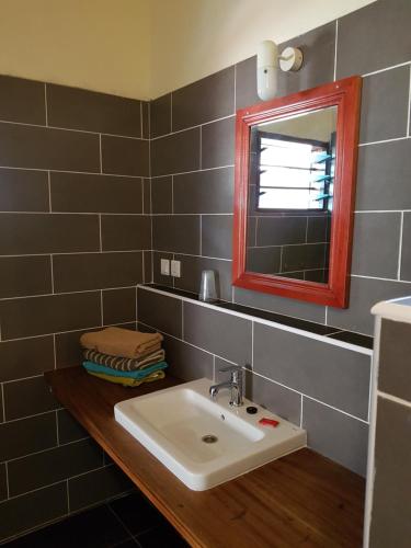 a bathroom with a sink and a mirror at Ko-Sa Beach Resort Ltd in Ampeni