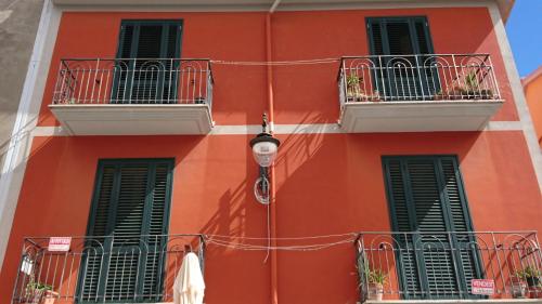 a red building with two balconies and a street light at Casa Vacanze Piazza Apartment 2 in SantʼAndrea di Conza