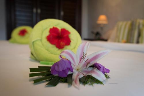a bouquet of flowers on a bed in a hotel room at Auberge d'Anse Boileau & Restaurant Chez Plume in Anse Boileau