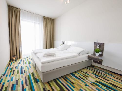 a bedroom with a white bed and a colorful rug at VacationClub - Baltic Park Molo Apartment D110 in Świnoujście