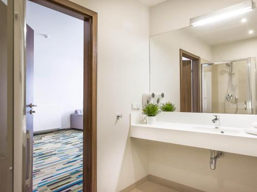 a bathroom with a sink and a mirror at VacationClub - Baltic Park Molo Apartment D110 in Świnoujście