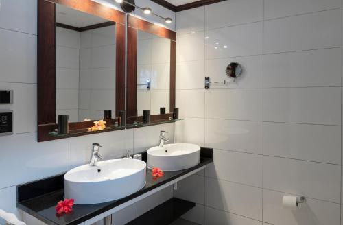 a bathroom with two sinks and a mirror at Auberge d'Anse Boileau & Restaurant Chez Plume in Anse Boileau