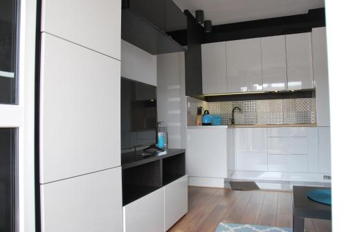 una cocina blanca con armarios blancos y negros en Margaret Apartments, en Cracovia