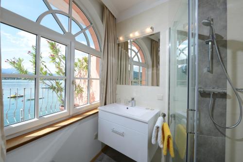 a bathroom with a sink and a shower and a window at Seehotel Astoria in Pörtschach am Wörthersee