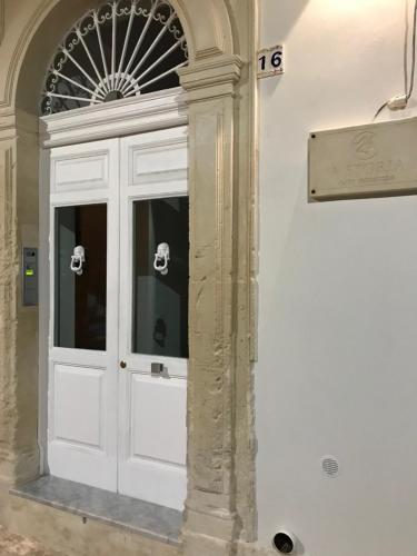 una porta bianca in un edificio con finestra di A'Storia a Siracusa