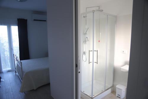 a glass shower in a bedroom with a bed at Il Gelso Country House in Castorano