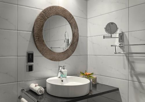 a white bathroom with a sink and a mirror at Auberge d'Anse Boileau & Restaurant Chez Plume in Anse Boileau