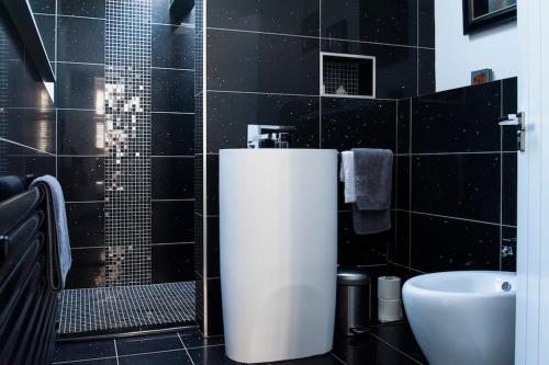 uma casa de banho com azulejos pretos, um lavatório e um WC. em Boutique house central Wells em Wells