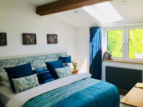 ein Schlafzimmer mit einem blauen Bett und einem Fenster in der Unterkunft Boutique cottage central Wells in Wells
