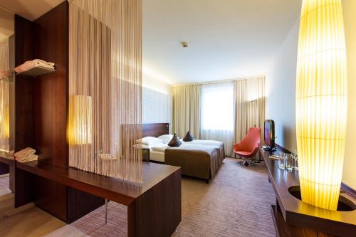 Habitación de hotel con cama y escritorio en Seepark Wörthersee Resort en Klagenfurt
