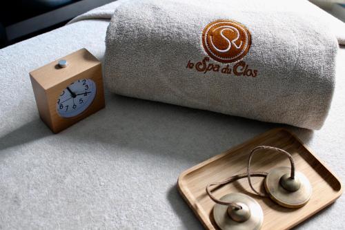 a clock on a bed next to a pillow and a wooden tray at Chateau du Clos de la Ribaudiere - Teritoria in Chasseneuil-du-Poitou