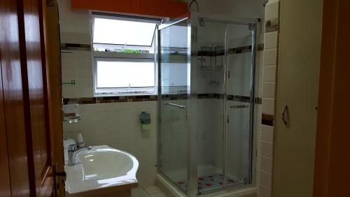 La salle de bains est pourvue d'une douche et d'un lavabo. dans l'établissement Hibiscus House Seychelles Self Catering, à Victoria