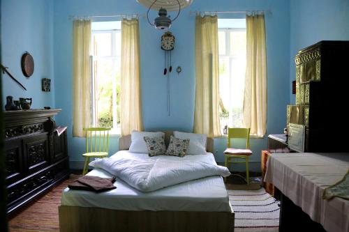 a bedroom with blue walls and a bed with two chairs at Casa Memoriala George Stephanescu in Căpăţîneni-Ungureni
