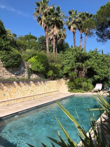 une piscine avec des palmiers en arrière-plan dans l'établissement L'Atelier, à Vence